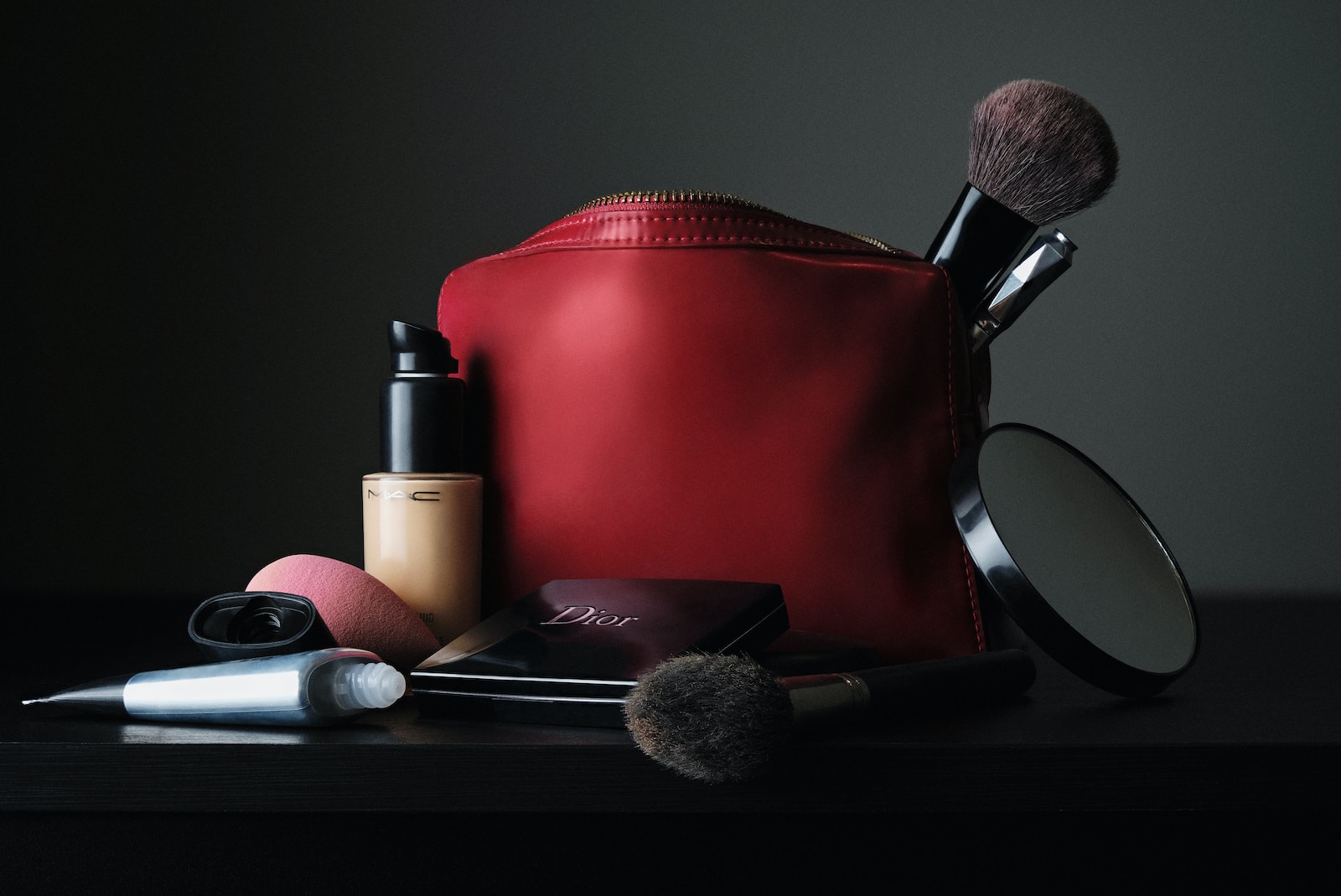 red leather bag beside black makeup brush